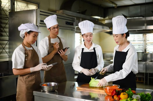 Cooking students attentively watching their teacher demonstrate food preparation techniques.