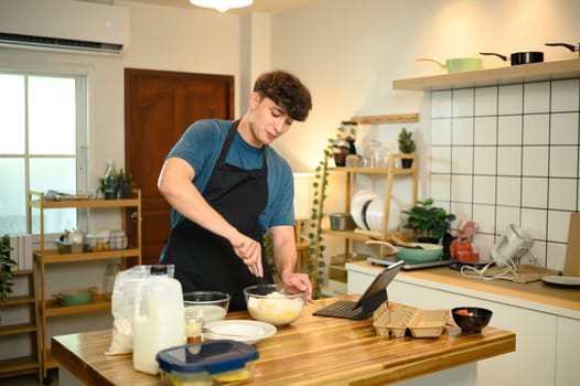 Caucasian man whisking batter for pancakes during a casual home cooking session.