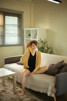 Curly haired woman having conversation on her mobile phone in a living room.