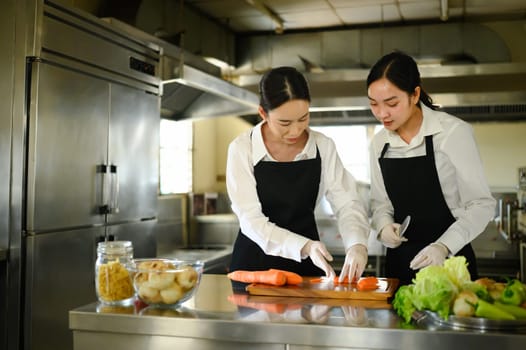 Culinary instructor guiding a student through carrot slicing during a practical cooking class.