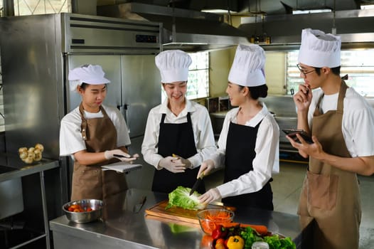 Chef teacher demonstrating vegetable preparation technique in a professional kitchen.