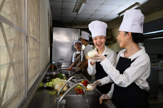 Smiling young chefs learning kitchen hygiene and teamwork in a professional cooking school.