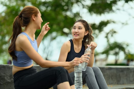 Active women in sportswear hydrating after completing their outdoor fitness routine.