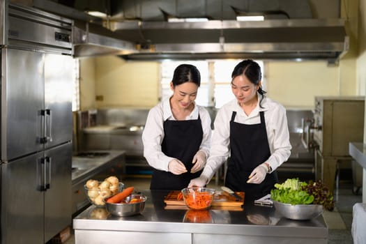 Culinary instructor guiding a student through carrot slicing during a practical cooking class.