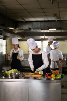 Chef apprentice working on vegetable preparation in a busy kitchen..