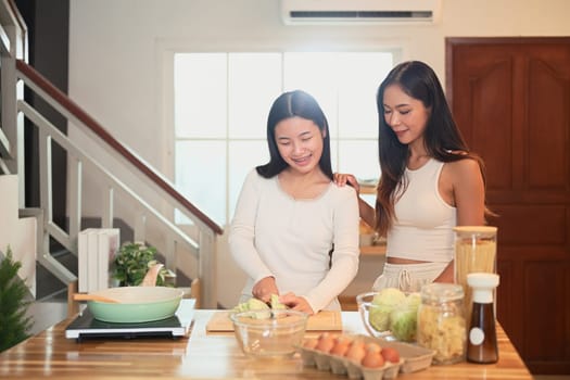 Young asian girl learning to cook with her mom in cozy home kitchen.