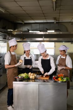Cooking students attentively watching their teacher demonstrate food preparation techniques.