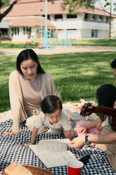 Happy family enjoying a picnic together on a blanket in the park.