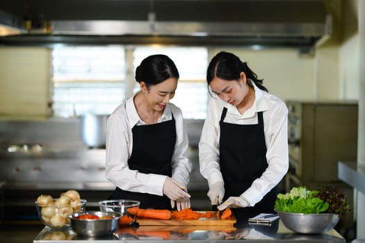 Culinary instructor guiding a student through carrot slicing during a practical cooking class.