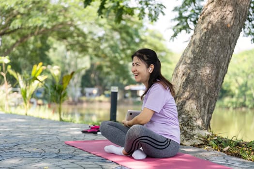 A joyful woman enjoys a moment of happiness on her yoga mat outdoors, embodying wellness and positivity in nature.