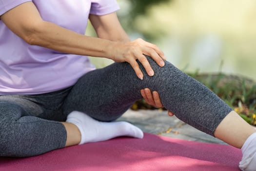 A woman engages in a gentle stretch, focusing on wellness and self-care in a serene outdoor setting.