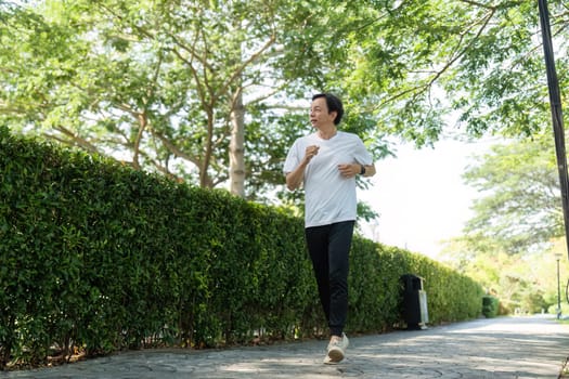 An elderly man enjoys a refreshing run in a park, showcasing his dedication to fitness and wellness.