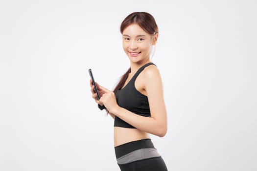 Phone ready and using her phone to check fitness progress, this athletic woman in black activewear blends gym strength and smartphone ease in one inspiring portrait. isolated studio white background