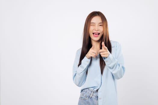 Cheeky woman makes a finger bang gesture as friendly woman winks and smiles, playfully pointing like she saying what up or you are the one, isolated on white background.