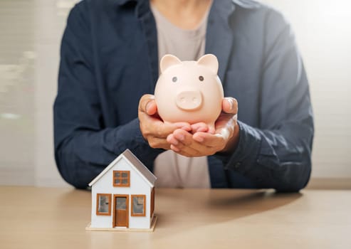 A close-up of hands with a piggy bank and house model, symbolizing saving money, financial planning, and property goals. Highlights mortgage options and homeownership strategies for a secure future.