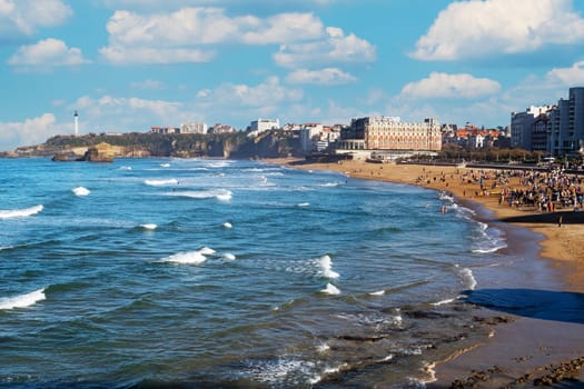 A beach with a large crowd of people and a beautiful blue ocean. Scene is peaceful and relaxing. Biarritz, France