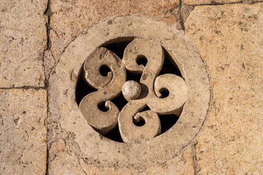 Close-up of an ornate stone manhole cover featuring a swirling, symmetrical design in the Roman Theatre in Amman