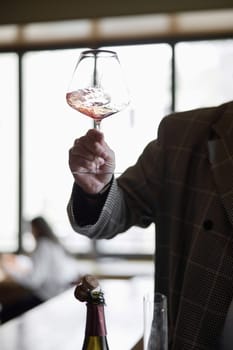 Champagne tasting in restaurant, A man holds in his hand a beautiful elegant glass with rose sparkling wine. High quality photo