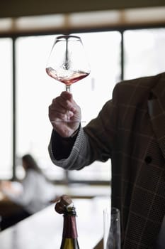 Champagne tasting in restaurant, A man holds in his hand a beautiful elegant glass with rose sparkling wine. High quality photo
