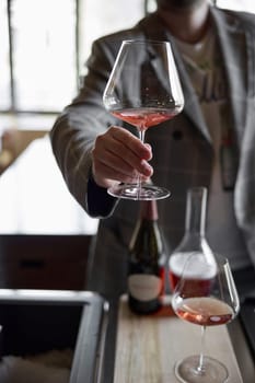 Champagne tasting in restaurant, A man holds in his hand a beautiful elegant glass with rose sparkling wine. High quality photo