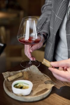 Champagne tasting in restaurant, A man holds in his hand a beautiful elegant glass with rose sparkling wine, He eats delicious snacks and drinks pink wine. High quality photo
