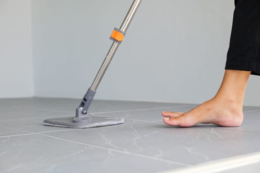 Woman mops the indoor floor, cleaning the front area of her home with a mop and rag. Housewife dedicated to maintaining cleanliness. Represents professional housekeeping and house maintenance concepts