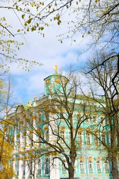the incredibly picturesque facade of the Winter Palace through the branches of trees on a clear spring day, the heritage of Russia, the most famous landmark of St. Petersburg, the museum. High quality photo