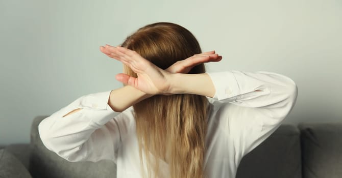 Close-up upset young woman shows stop, no or enough sign with palm of hand, refusal gesture, domestic violence