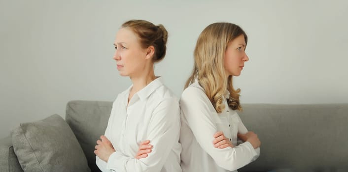 Upset offended caucasian two women, mature mother or sister and adult daughter crying together sitting on couch at home