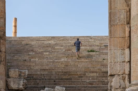Tourist clims the staircase past the altar terrace of Sanctuary of Artemis on Cardo Maximus in Jerash, a Greco-Roman well preserved city in Jordan
