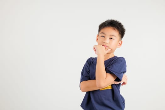 Portrait of an Asian kid boy deep in thought, standing with chin in hand, pondering a question. Studio shot isolated on white with ample copy space, primary child portraying contemplative expression