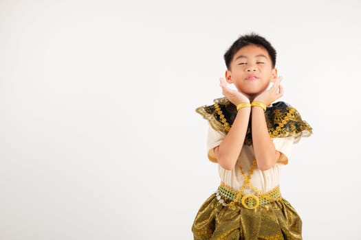 Portrait Thailand kid boy smiling traditional Thai dress costume raises her fists in celebration of her success, studio isolated white background, primary child saying yes with excitement winning
