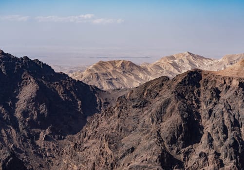 View from the top of the trail to the Monastery of rocky mountain range and gorges with Wadi Araba desert in distance