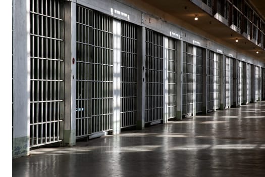A long hallway with many bars on the windows. The bars are white and the windows are clear