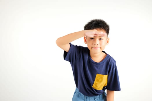 Searching concept. Asian young boy kid looking far away with hand over head at studio shot isolated on white background, Portrait of Happy primary child looking at distance with eyes shaded