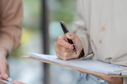 A close-up of a professional's hand taking notes on a clipboard, emphasizing the importance of ESG strategies in business planning.