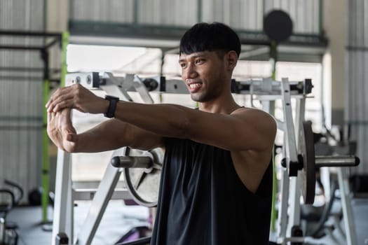 A focused young man performs a stretching exercise in a gym, emphasizing fitness and wellness. Ideal for health and exercise themes.