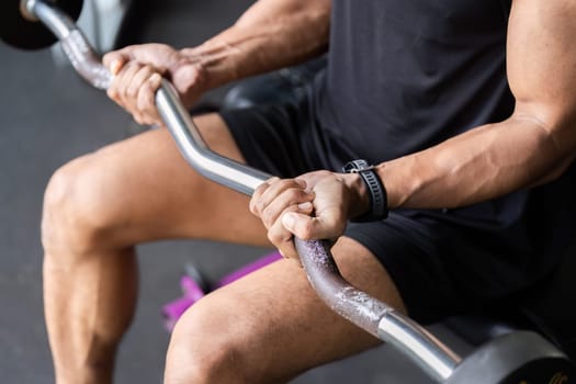 A dedicated male athlete grips a barbell, showcasing strength and focus during a fitness routine.