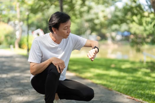 A middle-aged man monitors his fitness progress on a smartwatch while enjoying a day in the park, promoting wellness and active lifestyle.