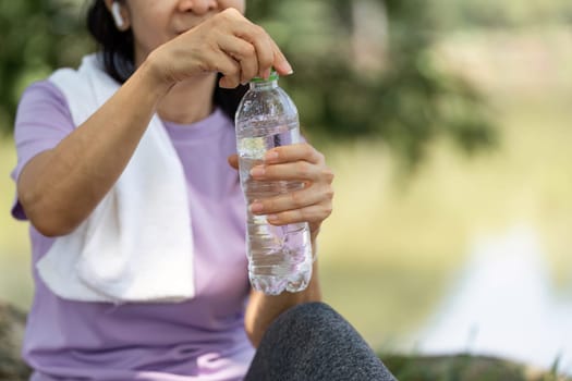 A woman prepares to drink water from a bottle, emphasizing hydration and wellness after exercising outdoors.