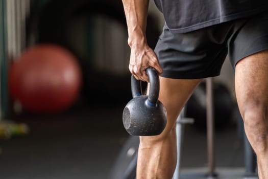 A fitness enthusiast lifts a kettlebell, showcasing strength and focus during a workout in a gym environment.