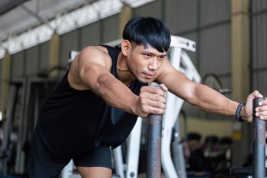 A dedicated male athlete leans forward on gym equipment, demonstrating strength and commitment to fitness.