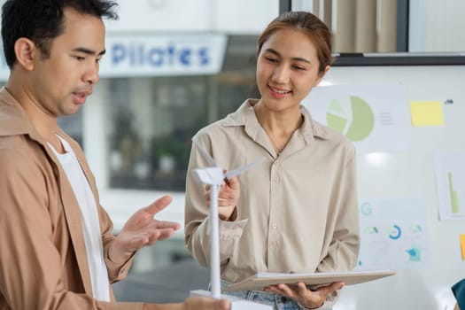 Two professionals engage in a discussion about a wind turbine model, focusing on sustainable practices and corporate ESG initiatives.