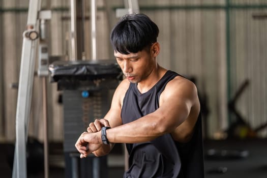 A focused individual checks their fitness tracker while preparing for a workout, emphasizing health and wellness.