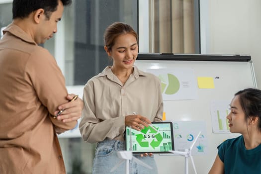 A confident woman presents ESG data on a tablet during a business meeting, emphasizing sustainability and corporate responsibility.