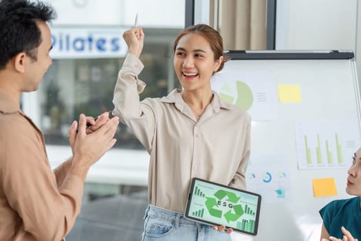 A woman raises her hand in excitement while presenting ESG data, fostering a positive and engaging atmosphere in the meeting.