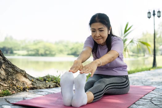 A young woman stretches her body on a yoga mat in a tranquil outdoor setting, promoting wellness and mindfulness.