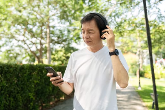 A middle-aged man listens to music with headphones in a park, promoting wellness and relaxation through music.