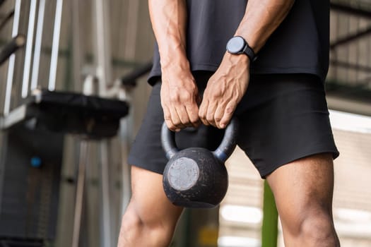 A dedicated fitness enthusiast lifts a kettlebell, showcasing strength and focus during a workout session in the gym.