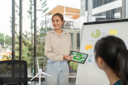 In a modern office, a woman discusses ESG strategies with her team, promoting sustainability and corporate responsibility.